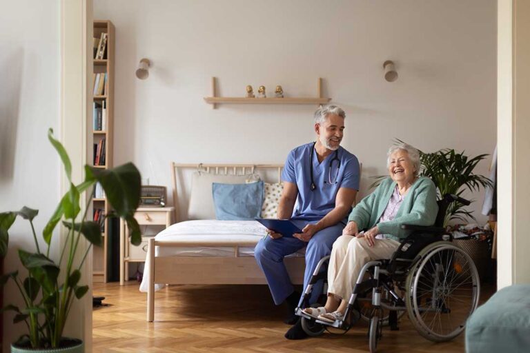 A group of seniors participating in a light exercise class with a fitness instructor in a bright community room.