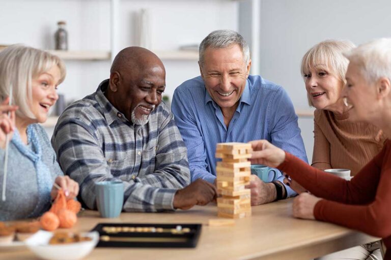 Senior couple sitting together on a cozy couch, smiling and holding hands in a sunlit living room.